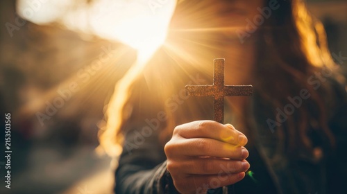 young woman holding a christian cross in warm sunlight symbolizing faith and hope