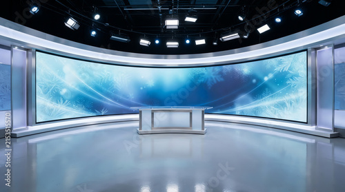 A modern news studio features a large curved digital screen and a minimalist desk.