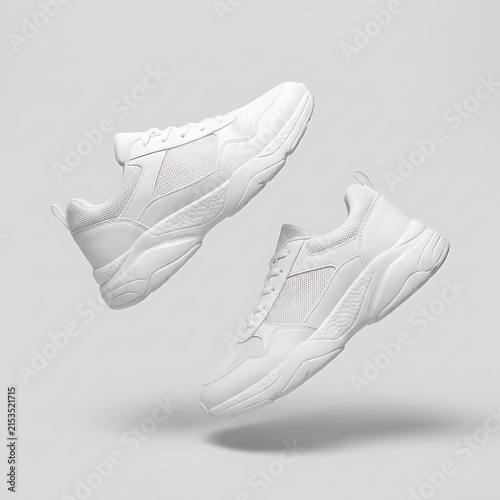 Pair of white chunky sneakers floating on a gray background
