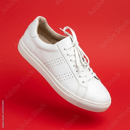Modern white leather sneaker floating on bright red background
