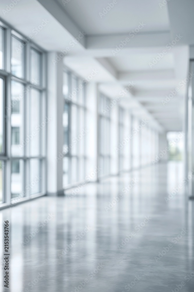 Fototapeta premium Empty modern office hallway with large windows and reflective floor, creating a bright minimalist atmosphere.