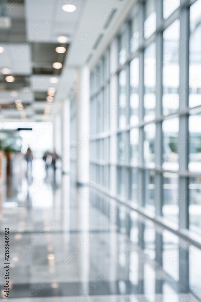 Fototapeta premium Blurred interior hallway with large windows and ceiling lights creating a modern architectural atmosphere