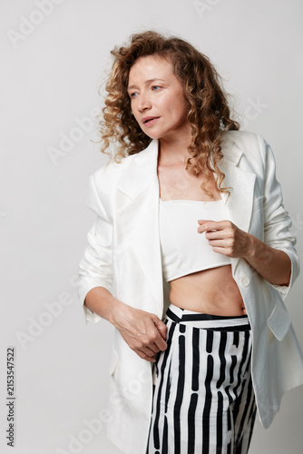 Foto An authentic middle-aged woman with natural skin poses in a white blazer and striped pants