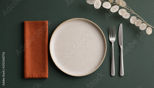 Minimalist table setting with ceramic plate, rust napkin and cutlery