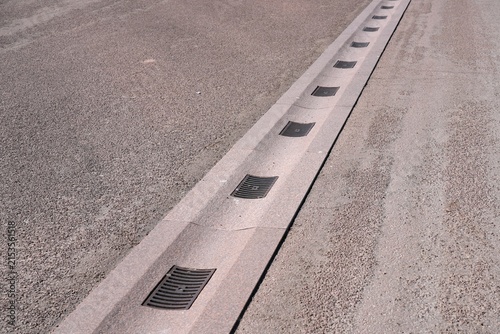 Photography Cast iron water drainage grates in a stone gutter