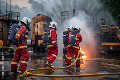 Cuadro en lienzo Firefighter Team Approaching Industrial Flames with Fire Hoses while Water Spray
