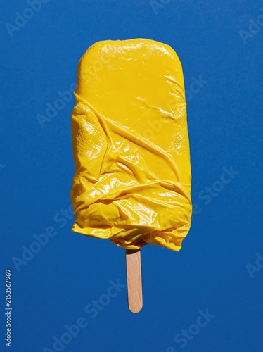 Yellow Rubber Glove Ice Pop with Smooth Central Panel on Cobalt Blue Background