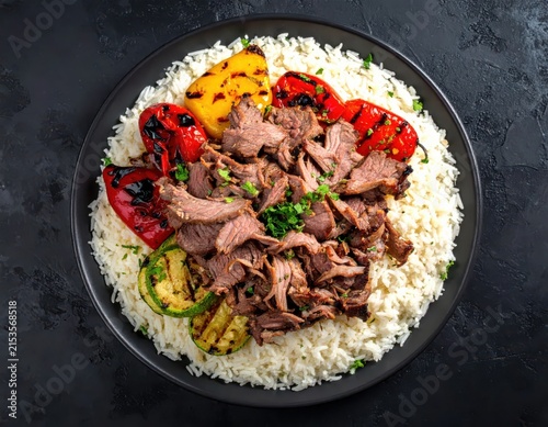 Grilled Meat and Vegetable Dish on Bed of Rice with Fresh Herbs and Garnish