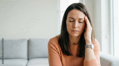 Sad woman headache pain stress fatigue couch home living room health problem discomfort exhaustion adult female casual sweater watch