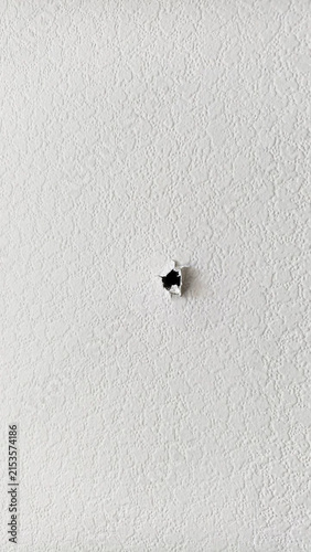Small hole in a white textured wall