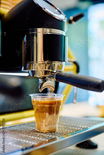 Espresso machine extracting fresh espresso into a plastic cup  mixing with milk to create a refreshing iced latte drink
