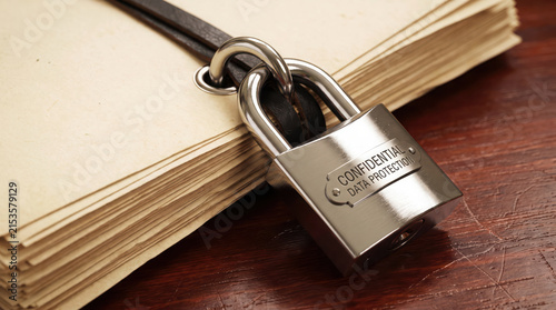 Steel padlock securing confidential data protection documents on wooden desk
