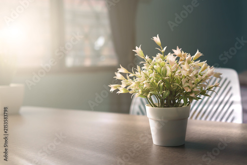 Bild auf Leinwand A vase of artificial flowers sits on a table in a room with warm, soft lighting, serving as a backdrop for the article