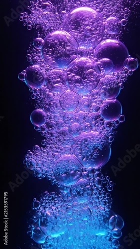 Abstract underwater bubbles rising in purple and blue light on a dark background.