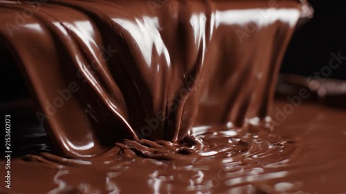 Glossy molten dark chocolate pooling and cascading in slow motion, rich texture