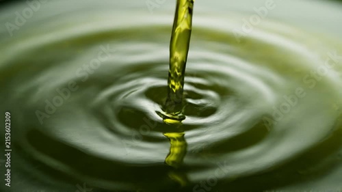 Golden olive oil pouring into water creating mesmerizing ripples in slow motion