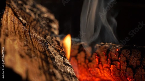 Close-up of smoldering aromatic wood burning with glowing embers and rising smoke