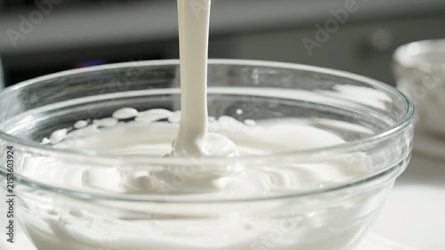 Smooth white cream being lifted from a glass bowl with a spoon in a kitchen setting