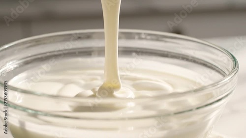 Close-up of a spoon lifting thick cream from a glass bowl on a kitchen surface