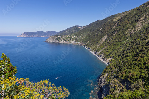 Cinque Terre along the rugged Ligurian shore in Italy shows long undeveloped coastal curve and deep water from an elevated hiking trail.