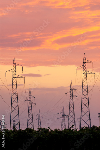 Tralicci elettrici al tramonto con cielo arancione