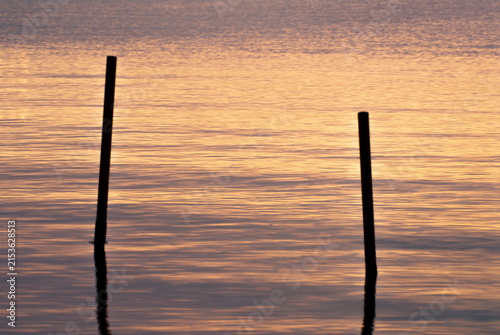 Due pali sommersi in acqua calma al tramonto