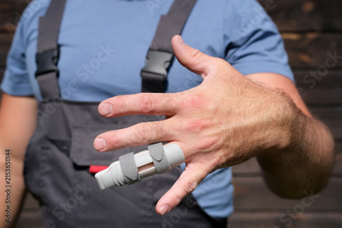 Photography Worker in protective workwear showing injured finger with splint after workplace