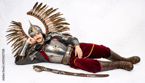 Man in silver plate armour with large eagle-feather wings reclining with a sabre and dagger, isolated on white background.
