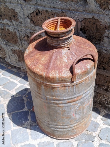 Fotografie Rusty Vintage Milk Churn Against Historic Architecture in Ronciglione
