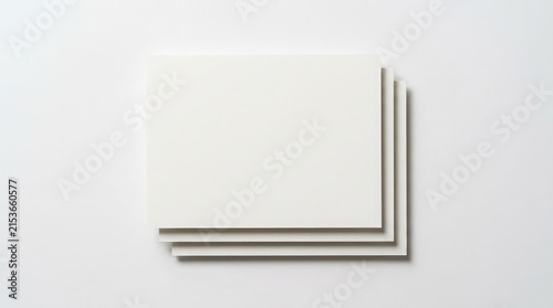 A top view of three blank white rectangular paper sheets stacked neatly on a clean light gray background for design presentation
