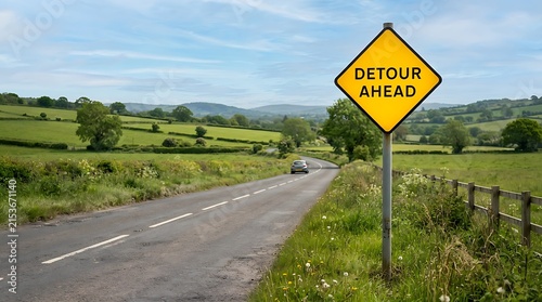 Yellow diamond detour ahead road sign standing on the side of a rural countryside road on a sunny summer day