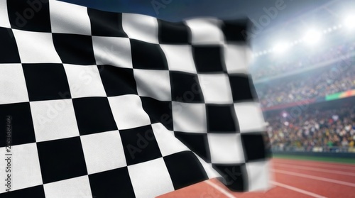 Waving checkered flag at a stadium with blurred crowd and track