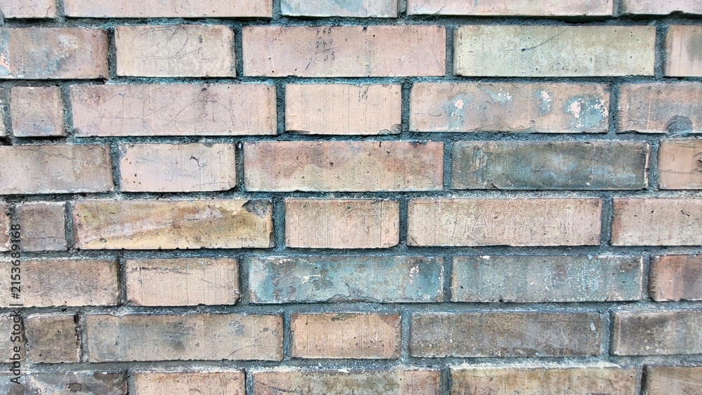 Fototapeta premium Weathered old stone wall with an aged brick texture in various soft natural pastel tones, creating a rustic architectural background with copy space.