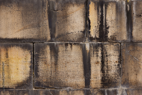 Close-up texture of ancient, weathered sandstone block wall with dark soot stains and rough masonry surface. Rustic, aged architectural background perfect for grunge design concepts, full frame view.