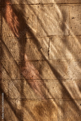 Warm rustic brick wall texture with handcrafted surfaces, earthy tones, natural sunlight and soft shadows creating an organic architectural background for interior design and visual projects.