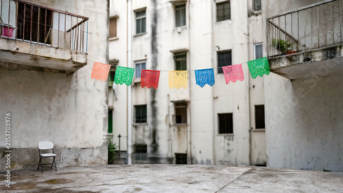 Colorful flags hanging in a rustic urban courtyard.
