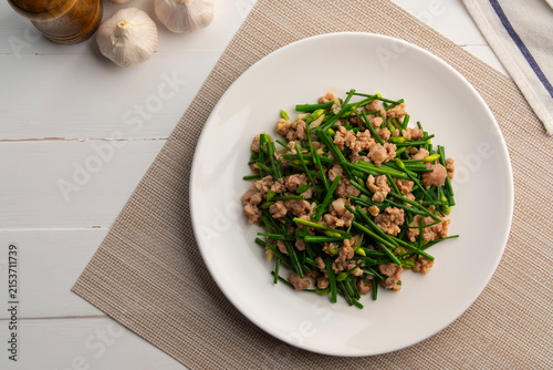 Stir-fried flowering garlic chives with minced pork in white plate.Top view.