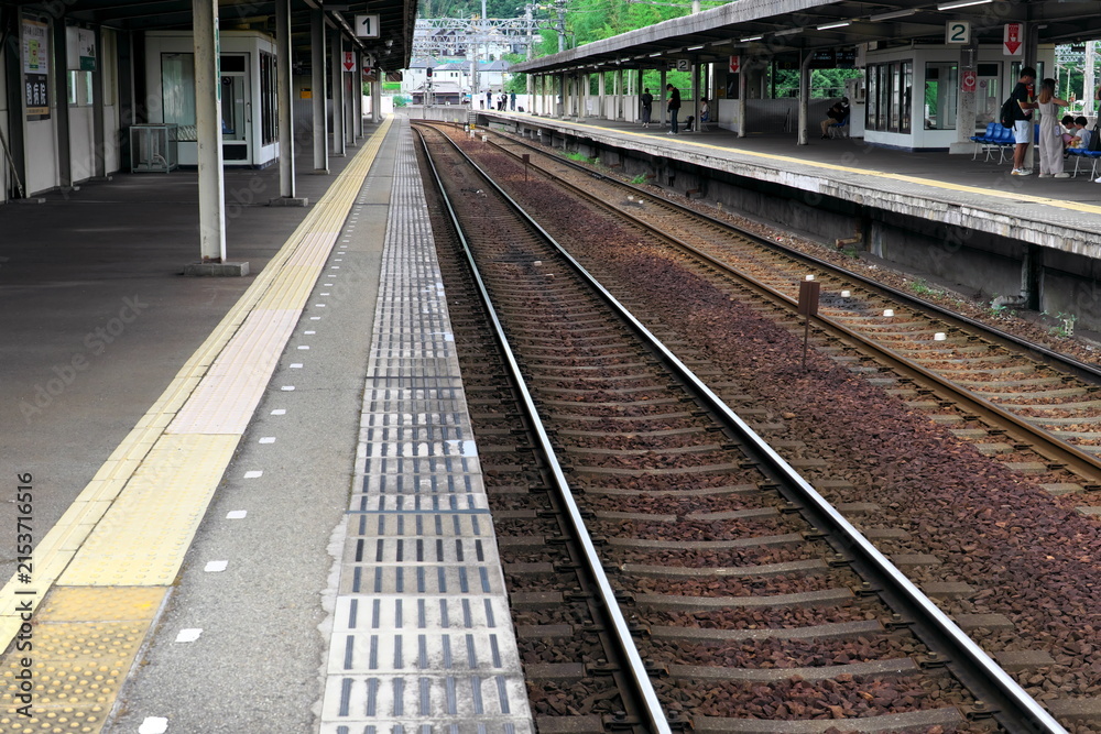 Fototapeta premium 通勤客が電車を待つ郊外の駅のプラットホームと線路