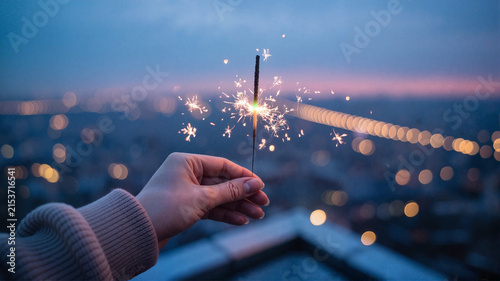 sparkler hand city skyline night celebration light bright dusk evening festive holiday glow magic outdoor bokeh view joy fireworks party