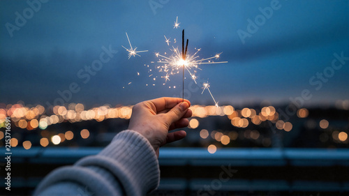 hand sparkler night lights city celebration outdoor joy evening glow winter new year firework fun festive bright bokeh happiness excitement warmth texture sparkle decorative light event