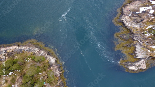 Quadro su tela Straight down drone aerial view of a narrow sea strait with water current between rocky island shores