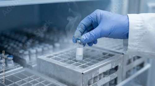 Scientist holding a frozen vial from a cryogenic freezer in a laboratory