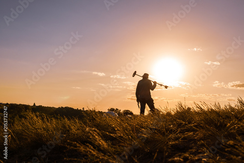 Treasure Hunter Resting His Detector Against a Glowing Evening Sky