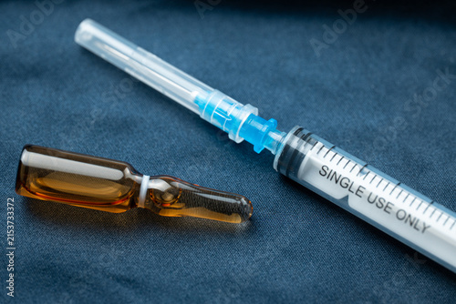 Obraz na plátně Medical syringe and ampoule placed on a dark surface