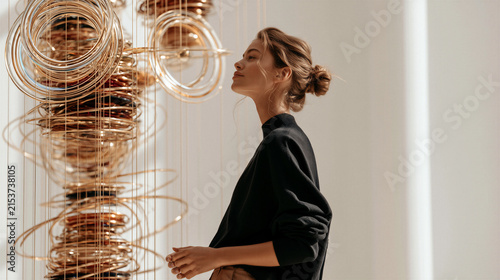 Young Blonde Woman Contemplating Sculpture in Contemporary Art Gallery