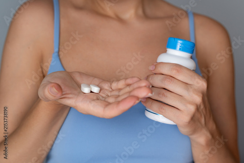Young woman holding pill bottle and white tablets in palm, vitamins and medication concept, healthcare and daily supplementation