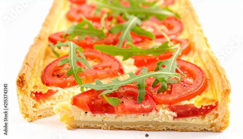 Rectangular savory tart with flaky crust, topped with tomato slices, creamy cheese layer, and fresh arugula garnish, appetizing and colorful dish.