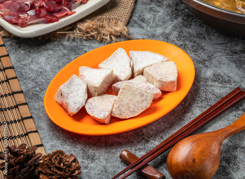 Fresh raw taro root chunks on an orange plate for hot pot cooking