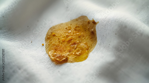 Close-up of a sticky, yellowish-brown stain on a white fabric surface.