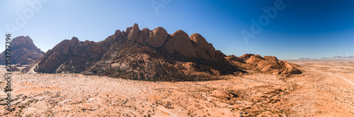 Fotografie Aerial panoramic view of massive granite rock formations and dry desert plains at Spitzkoppe in Namibia under clear sky